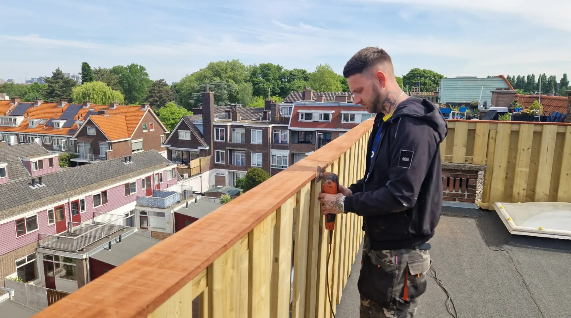 Dakdekker werkt aan een houten balustrade op het dakterras
